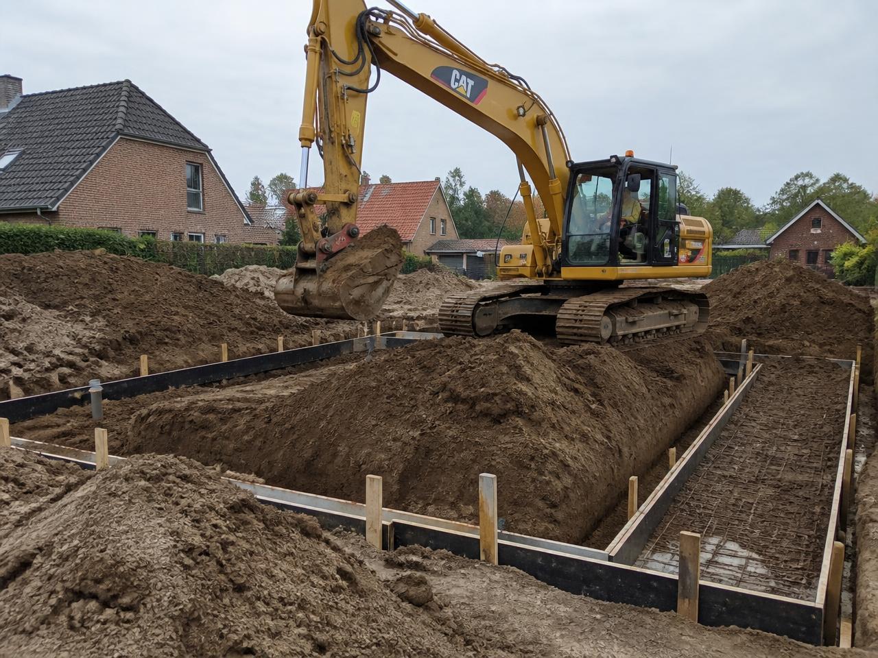 Graafmachine graaft de funderingssleuven van een nieuwbouwwoning