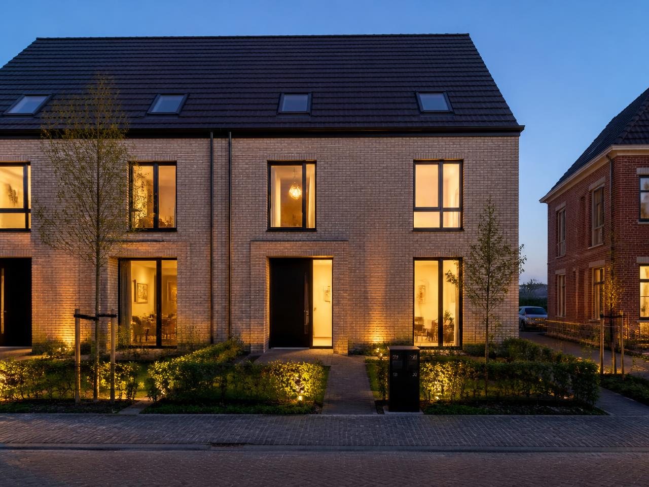 Afgewerkte nieuwbouwwoning met verlichte gevel in de avond